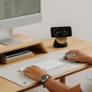 A clean and modern desk setup featuring a computer, clock, and accessories in a home office.