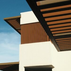 A contemporary building showcasing geometric design and wooden accents against a clear blue sky.